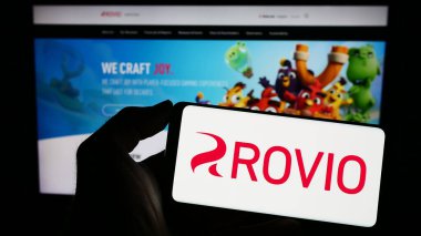 Stuttgart, Almanya - 03-31-2023: İnternet sayfasının önünde Fin oyun şirketi Rovio Entertainment Oyj 'un logosuyla cep telefonu tutan kişi. Telefon ekranına odaklan.
