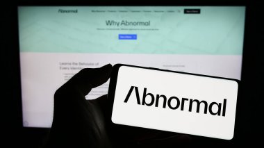 Stuttgart, Almanya - 03-31-2023: ABD 'li şirket Anormal Güvenlik Şirketi' nin logosuyla cep telefonu sahibi kişi iş sayfasının önünde ekranda görülüyor. Telefon ekranına odaklan.