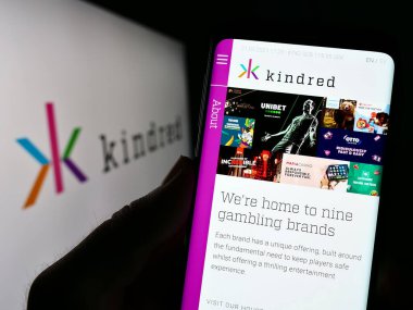 Stuttgart, Almanya - 04-01-2023: Çevrimiçi kumar şirketi Kindred Group plc 'nin internet sitesi ile akıllı telefon sahibi kişi logonun önünde ekranda. Telefon ekranının merkezine odaklan.
