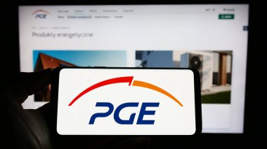 Stuttgart, Almanya - 04-01-2023: PGE Polska Grupa Energetyczna SA şirketinin logosuna sahip cep telefonu sahibi kişi iş sayfasının önünde ekranda görülüyor. Telefon ekranına odaklan.