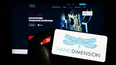 Stuttgart, Almanya - 04-01-2023: Nano Boyut Teknolojileri Ltd. şirketinin logosuyla cep telefonu sahibi kişi iş sayfasının önünde ekranda. Telefon ekranına odaklan.