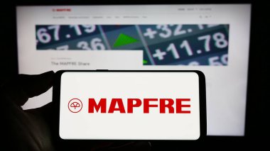 Stuttgart, Almanya - 04-01-2023: İspanyol sigorta şirketi Mapfre SA 'nın logosunun bulunduğu cep telefonu sahibi kişi iş sayfasının önünde ekranda. Telefon ekranına odaklan.