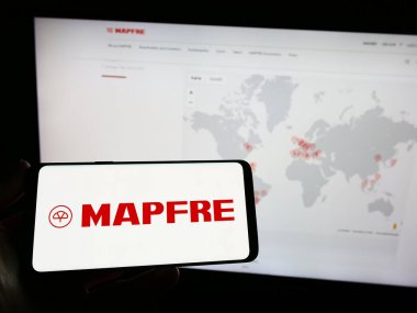 Stuttgart, Almanya - 04-01-2023: İspanyol sigorta şirketi Mapfre S.A. 'nın logosunun bulunduğu akıllı telefonu web sitesinin önünde tutan kişi. Telefon ekranına odaklan.