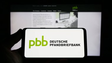 Stuttgart, Almanya - 04-01-2023: Web sitesi önünde üzerinde Deutsche Pfandbriefbank AG (PBB) logosu bulunan kişi. Telefon ekranına odaklan.