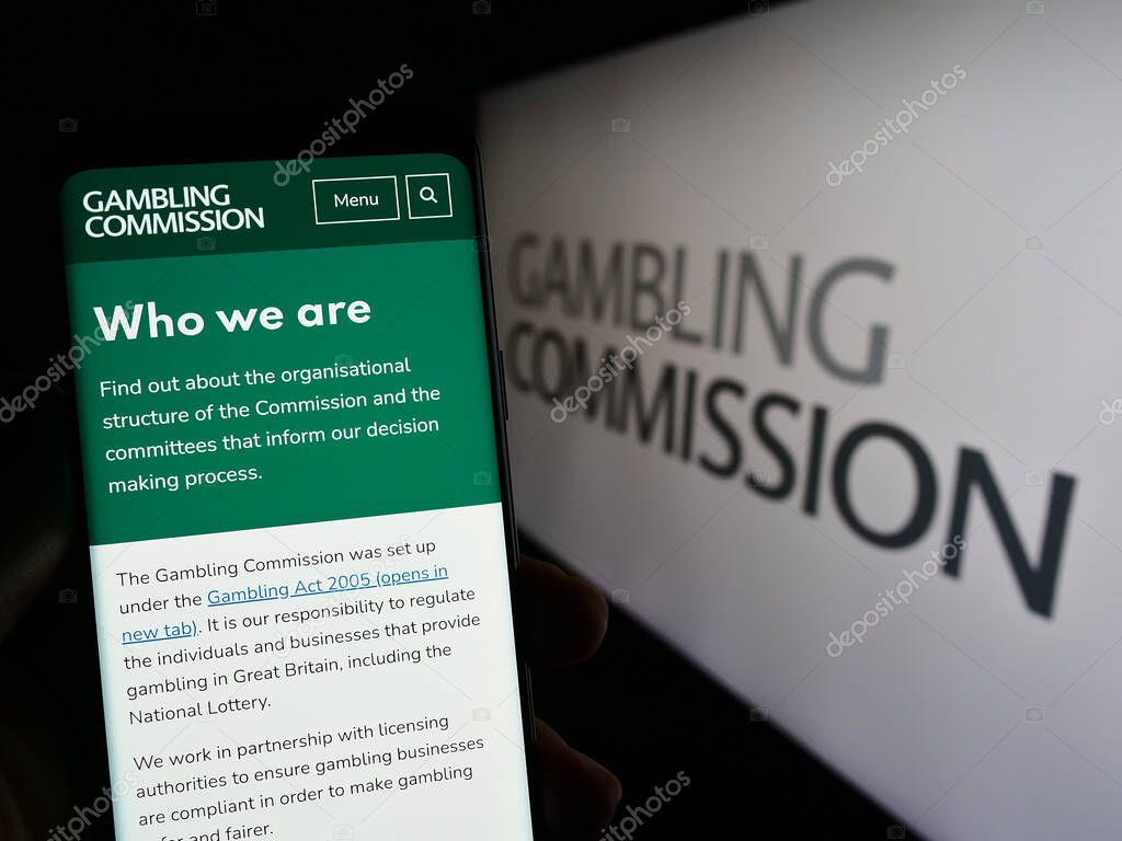 Stuttgart, Germany - 04-01-2023: Person holding smartphone with web page of British public body Gambling Commission on screen in front of logo. Focus on center of phone display.