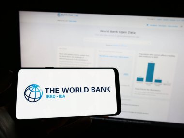 Stuttgart, Almanya - 04-02-2023: Finans kurumu logosu olan cep telefonu sahibi kişi The World Bank iş dünyasının web sayfasının önünde ekranda. Telefon ekranına odaklan.