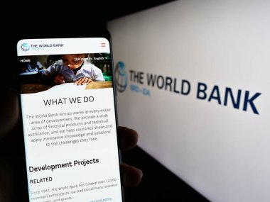 Stuttgart, Almanya - 04-02-2023: Finans kurumu The World Bank 'ın logo önündeki web sayfası ile akıllı telefon tutan kişi. Telefon ekranının merkezine odaklan.