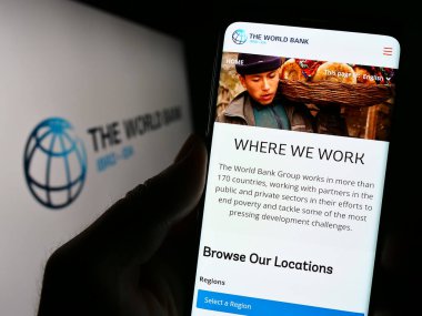 Stuttgart, Almanya - 04-02-2023: Finans kurumunun web sitesi The World Bank 'ın logo önünde cep telefonu tutan kişi. Telefon ekranının merkezine odaklan.