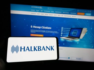 Stuttgart, Almanya - 04-02-2023: İnternet sitesi önünde Türk Halk Bankası A.S. (Halkbank) logosuna sahip akıllı telefon sahibi kişi. Telefon ekranına odaklan.