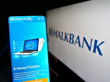 Stuttgart, Almanya - 04-02-2023: Türkiye Halk Bankasi A.S. (Halkbank) adlı şirketin internet sitesiyle cep telefonu elinde bulunan kişi logo ile ekranda. Telefon ekranının merkezine odaklan.