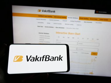 Stuttgart, Almanya - 04-02-2023: Türkiye Vakflar T.A.O. logosuna sahip cep telefonu sahibi kişi (VakıfBank) web sayfasının önünde ekranda. Telefon ekranına odaklan.