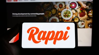 Stuttgart, Almanya - 04-02-2023: Sitenin önünde ekranda Kolombiyalı gıda dağıtım şirketi Rappi Inc. 'in logosunu taşıyan kişi. Telefon ekranına odaklan.