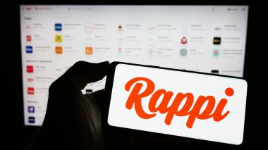 Stuttgart, Almanya - 04-02-2023: İş sayfası önünde ekranda Kolombiyalı gıda dağıtım şirketi Rappi Inc. 'in logosuyla cep telefonu tutan kişi. Telefon ekranına odaklan.