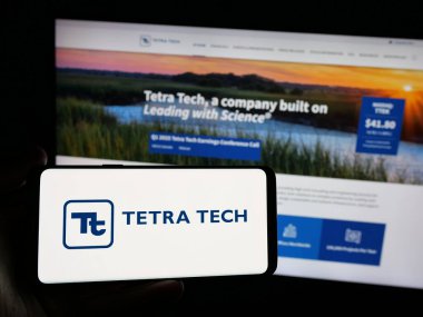 Stuttgart, Almanya - 01-15-2025: ABD 'li mühendislik şirketi Tetra Tech Inc.' in logosunu elinde tutan kişi web sitesinin önünde ekranda. Telefon ekranına odaklan.