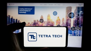 Stuttgart, Almanya - 01-15-2025: ABD 'li mühendislik şirketi Tetra Tech Inc.' in logosuyla cep telefonu sahibi kişi iş sayfasının önünde ekranda. Telefon ekranına odaklan.
