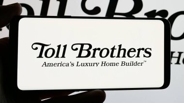 Stuttgart, Germany - 01-15-2025: Smartphone with logo of US homebuilding company Toll Brothers Inc. on screen. Focus on phone display. clipart