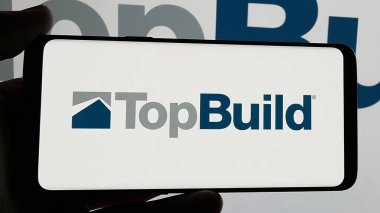 Stuttgart, Germany - 01-15-2025: Smartphone with logo of US building materials company TopBuild Corp. on screen. Focus on phone display. clipart