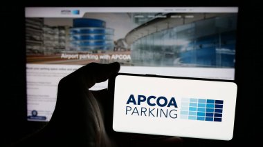 Stuttgart, Almanya - 01-15-2025: Alman firması APCOA Park Holding 'in logosunun bulunduğu cep telefonu sahibi kişi iş sayfasının önünde ekranda. Telefon ekranına odaklan.