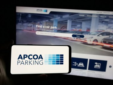 Stuttgart, Almanya - 01-15-2025: Alman APCOA Park Holding GmbH logosuna sahip akıllı telefon sahibi kişi web sitesinin önünde ekranda. Telefon ekranına odaklan.