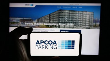 Stuttgart, Almanya - 01-15-2025: Alman firması APCOA Park Holding 'in logosunun bulunduğu cep telefonu sahibi kişi iş sayfasının önünde ekranda. Telefon ekranına odaklan.