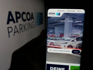 Stuttgart, Almanya - 01-15-2025: Alman APCOA Otopark Holding 'in web sayfası olan akıllı telefon sahibi kişi logonun önünde ekranda. Telefon ekranının merkezine odaklan.