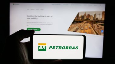 Stuttgart, Almanya - 01-16-2025: Petroleo Brasileiro SA (Petrobras) şirketinin logosuyla cep telefonu sahibi kişi iş sayfasının önünde ekranda. Telefon ekranına odaklan.