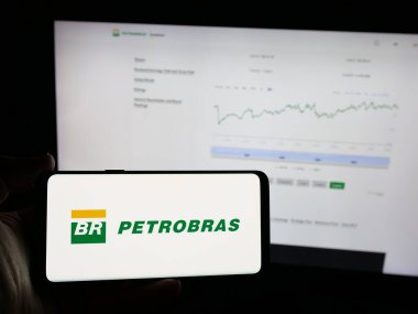 Stuttgart, Almanya - 01-16-2025: Web sitesi önünde Petroleo Brasileiro S.A. (Petrobras) şirketinin logosuna sahip akıllı telefon sahibi kişi. Telefon ekranına odaklan.