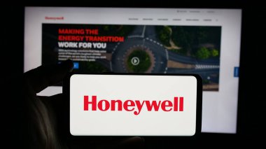 Stuttgart, Almanya - 01-16-2025: ABD 'li Honeywell International Inc. şirketinin logosuyla cep telefonu sahibi kişi iş sayfasının önünde ekranda. Telefon ekranına odaklan.