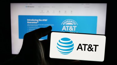 Stuttgart, Almanya - 01-16-2025: ABD telekomünikasyon şirketi ATT Inc. 'nin logosunu taşıyan cep telefonu sahibi kişi web sitesinin önünde ekranda. (AT ve T) Telefon ekranına odaklan.
