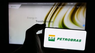 Stuttgart, Almanya - 01-16-2025: Web sayfası önünde Petroleo Brasileiro S.A. (Petrobras) şirketinin logosunun bulunduğu cep telefonu sahibi kişi. Telefon ekranına odaklan.