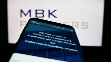 Stuttgart, Almanya - 03-22-2023: Koreli yatırım şirketi MBK Partners Ltd. 'nin web sitesiyle birlikte cep telefonu iş logosu önünde ekranda. Telefon ekranının sol üst kısmına odaklan.
