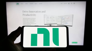 Stuttgart, Almanya - 03-23-2023: Web sitesi önünde National Instruments Corporation (NI) şirketinin logosunu elinde tutan kişi. Telefon ekranına odaklan.