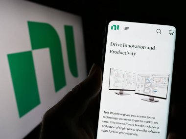 Stuttgart, Almanya - 03-23-2023: National Instruments Corporation (NI) şirketinin web sitesi ile akıllı telefon sahibi kişi ekranda logolu. Telefon ekranının merkezine odaklan.