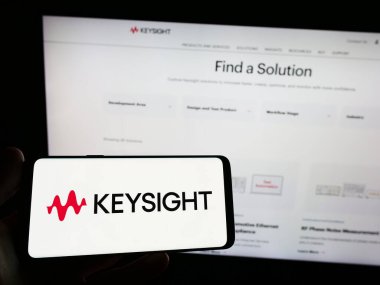 Stuttgart, Almanya - 03-23-2023: ABD 'li Keysight Technologies Inc. şirketinin logosunu elinde tutan kişi web sitesinin önünde ekranda. Telefon ekranına odaklan.
