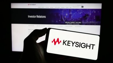 Stuttgart, Almanya - 03-23-2023: ABD 'li Keysight Technologies Inc. şirketinin logosuyla cep telefonu sahibi kişi iş sayfasının önünde ekranda. Telefon ekranına odaklan.