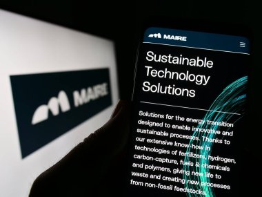 Stuttgart, Almanya - 03-23-2023: İtalyan şirketi Maire Tecnimont S.P.A. 'nın internet sayfası ile akıllı telefon sahibi kişi logo önünde ekranda. Telefon ekranının merkezine odaklan.
