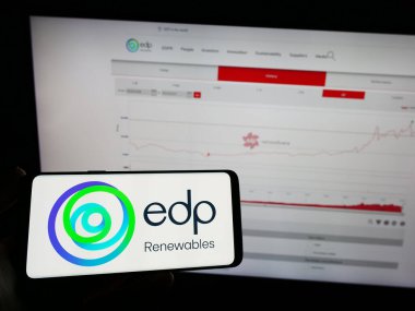 Stuttgart, Almanya - 03-24-2023: İnternet sayfası önünde EDP Renovaveis SA (EDPR) logosuna sahip cep telefonu sahibi kişi. Telefon ekranına odaklan.