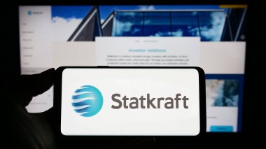 Stuttgart, Almanya - 03-24-2023: Norveçli hidroelektrik şirketi Statkraft AS 'in logosuyla cep telefonu sahibi kişi iş sayfasının önünde ekranda görülüyor. Telefon ekranına odaklan.