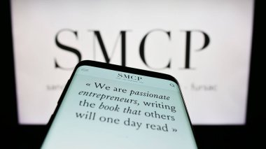 Stuttgart, Almanya - 03-25-2023: Fransız lüks moda şirketi SMCP S.A. 'nın web sitesi olan cep telefonu iş logosu önünde ekranda. Telefon ekranının sol üst kısmına odaklan.