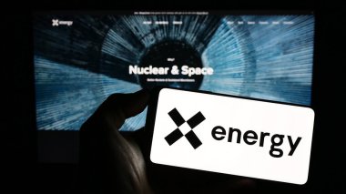 Stuttgart, Almanya - 03-25-2023: ABD 'li nükleer enerji şirketi X Energy LLLC' nin logosuyla cep telefonu sahibi kişi iş sayfasının önünde ekranda. Telefon ekranına odaklan.