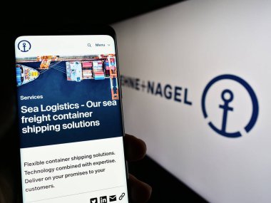 Stuttgart, Almanya - 03-25-2023: Lojistik şirketi Kuehne Nagel International AG 'nin web sayfası ile cep telefonu tutan kişi logolu ekranda. Telefon ekranının merkezine odaklan.