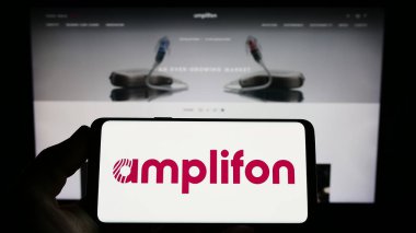 Stuttgart, Almanya - 03-25-2023: İtalyan işitme cihazı şirketi Amplifon S.P.A. 'nın logosunu taşıyan kişi web sitesinin önünde ekranda. Telefon ekranına odaklan.