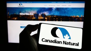 Stuttgart, Almanya - 03-25-2023: Kanada Doğal Kaynaklar Şirketi logosuna sahip akıllı telefon sahibi kişi web sitesinin önünde ekranda. Telefon ekranına odaklan.