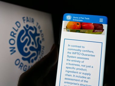 Stuttgart, Almanya - 03-25-2023: Dünya Fuarı Ticaret Örgütü 'nün (WFTO) web sayfası olan cep telefonu logosu önünde ekranda. Telefon ekranının merkezine odaklan.