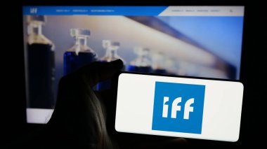 Stuttgart, Almanya - 01-17-2025: İnternet sayfası önünde üzerinde International Flavors Fragrances Inc. (IFF) şirketinin logosu bulunan cep telefonu sahibi kişi. Telefon ekranına odaklan.