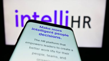 Stuttgart, Almanya - 03-25-2023: Avustralyalı şirket IntelliHR Systems Pty 'nin web sitesiyle cep telefonu. Ltd. Logonun önünde ekranda. Eğer telefon görüntüsü varsa sol üstte odaklan.
