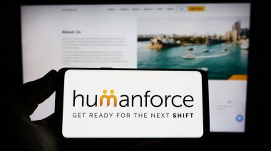 Stuttgart, Almanya - 03-25-2023: Avustralyalı yazılım şirketi Humanforce 'un logosunu elinde tutan kişi web sitesinin önünde ekranda. Telefon ekranına odaklan.