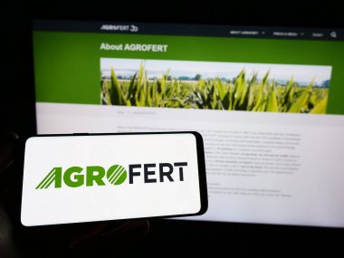 Stuttgart, Germany - 03-25-2023: Person holding smartphone with logo of Czech company Agrofert a.s. on screen in front of website. Focus on phone display. clipart