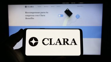 Stuttgart, Almanya - 03-25-2023: Meksikalı fintech şirketi Clara 'nın logosunu elinde tutan kişi web sitesinin önünde ekranda. Telefon ekranına odaklan.