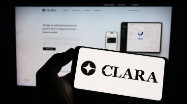 Stuttgart, Almanya - 03-25-2023: Meksikalı fintech şirketi Clara 'nın logosunun bulunduğu cep telefonu sahibi kişi iş sayfasının önünde ekranda. Telefon ekranına odaklan.